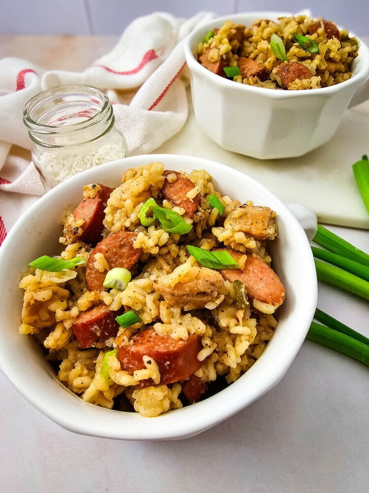 Delicious sausage fried rice with green onions in white bowls.