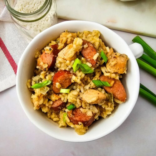 Delicious creamy chicken and sausage rice bowl garnished with green onions.