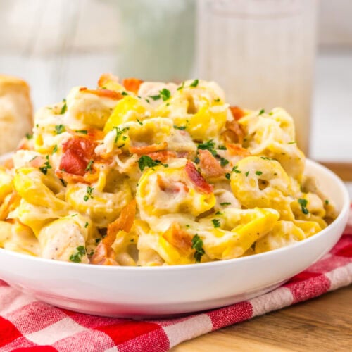 Delicious creamy chicken salad with bacon, herbs, and cheese in a white bowl.