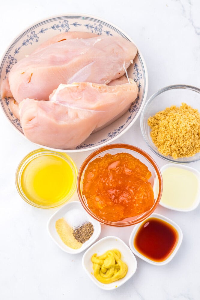 Slow cooker apricot brown sugar chicken ingredients laid out including raw chicken breasts and measured seasonings