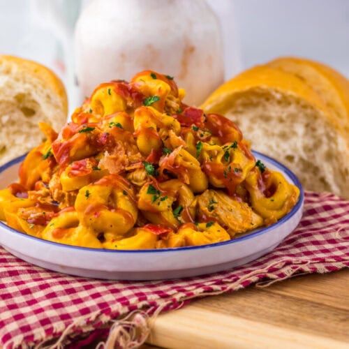 Delicious creamy chicken pasta served in a bowl with bread on a wooden table.