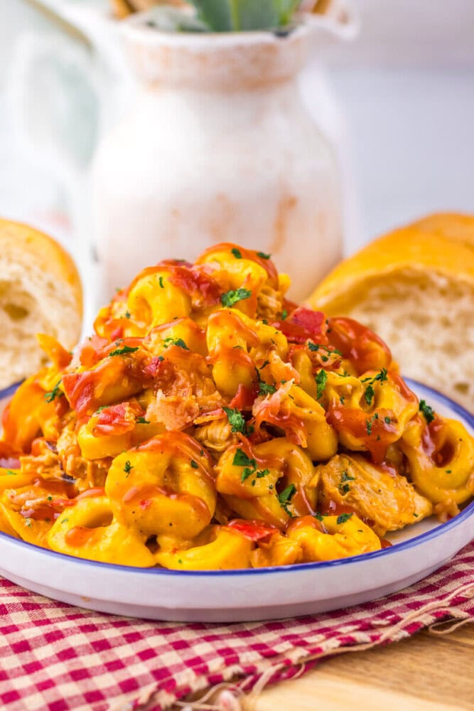 Delicious creamy chicken pasta with vegetables and herbs in a white bowl.