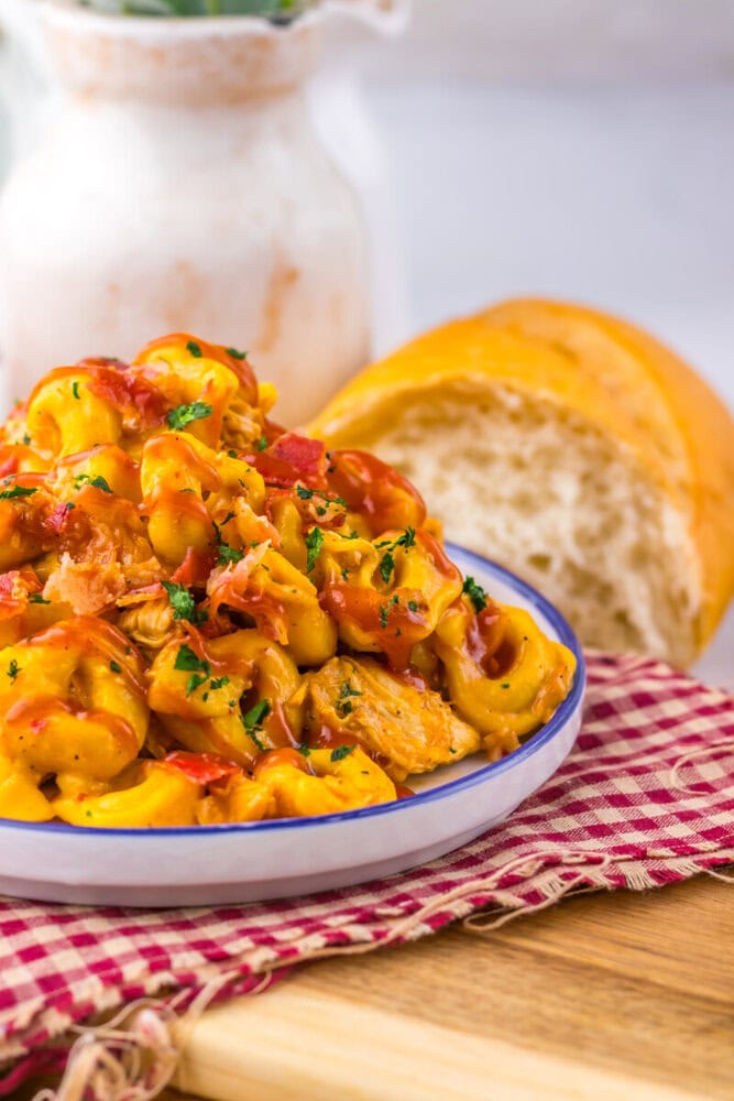 Delicious creamy chicken pasta with vegetables served with bread on a rustic table.