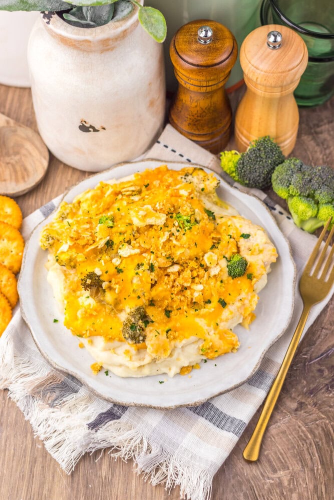 Delicious cauliflower casserole topped with broccoli and cheese, served on a rustic plate.