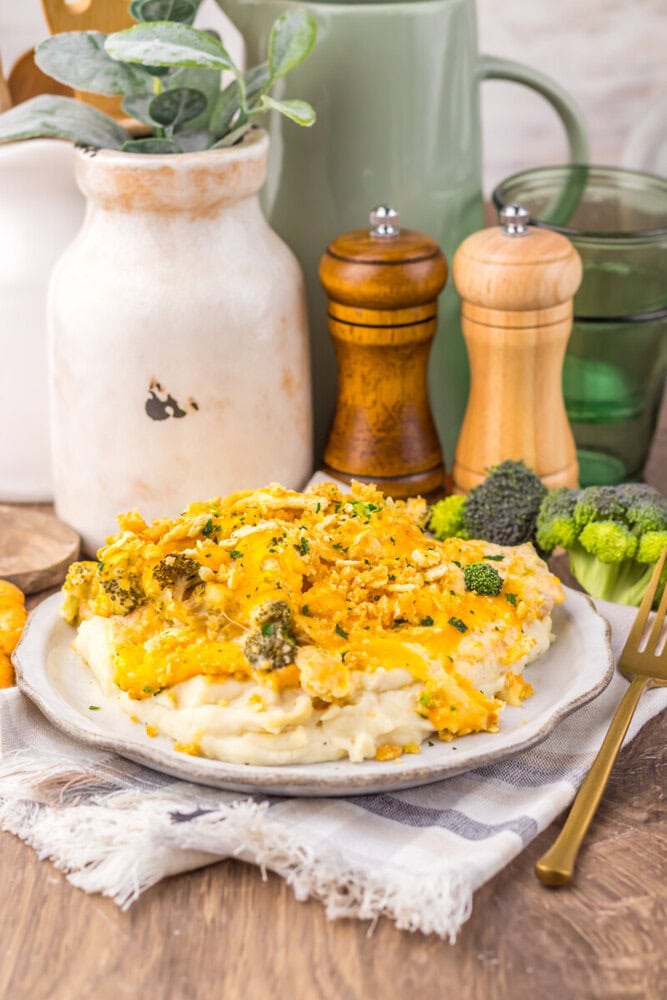 Delicious mashed potatoes topped with broccoli and melted cheese, served on a rustic plate.
