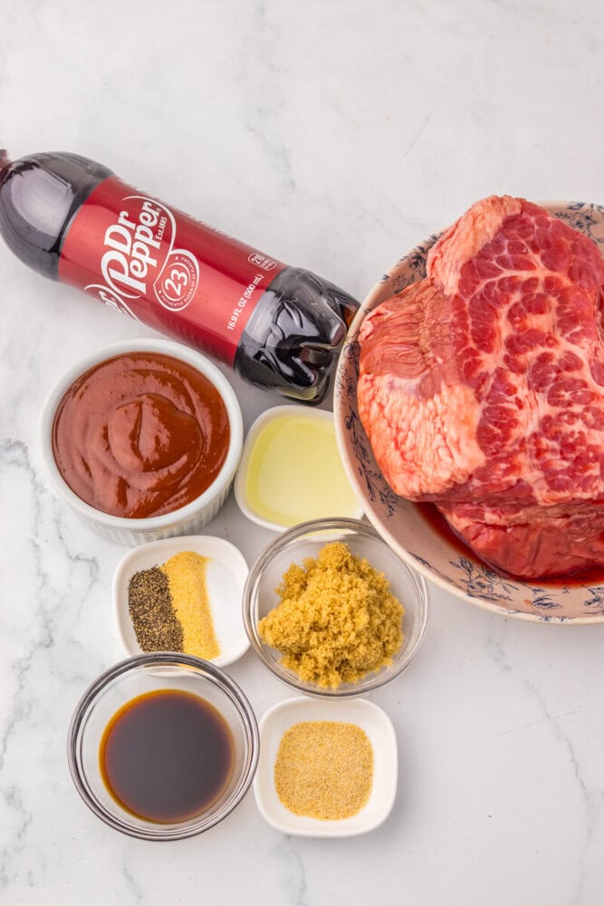 Marinated steak with BBQ sauce, spices, and oil on a white marble surface.