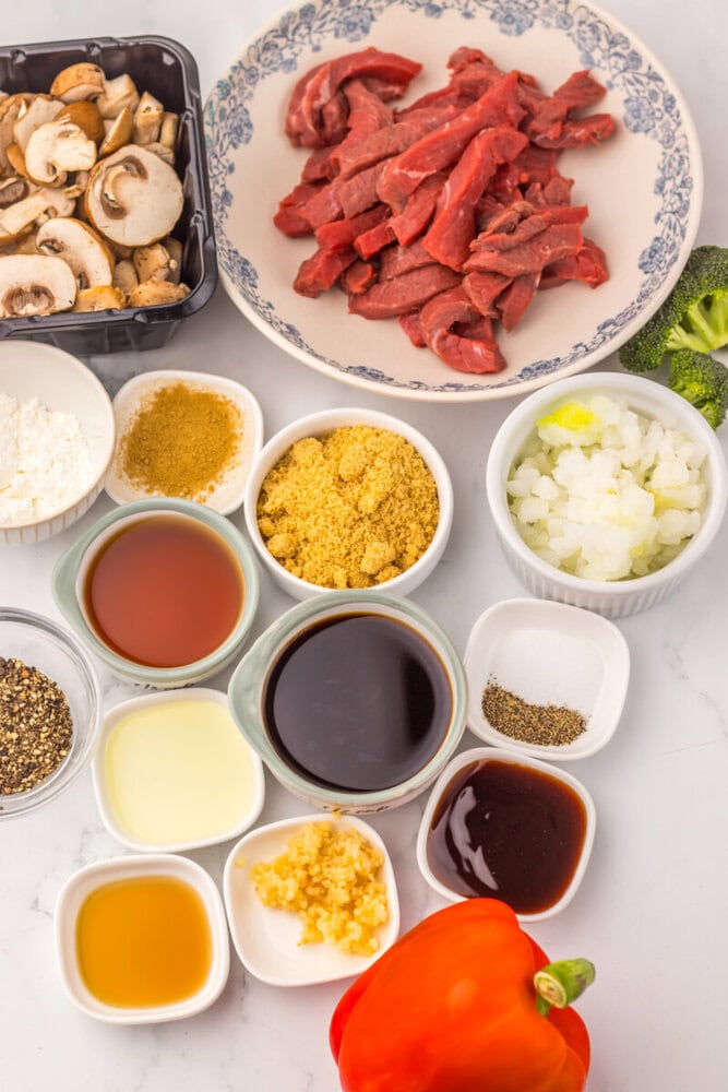 Fresh sliced beef, mushrooms, vegetables, and sauces for stir-fry.