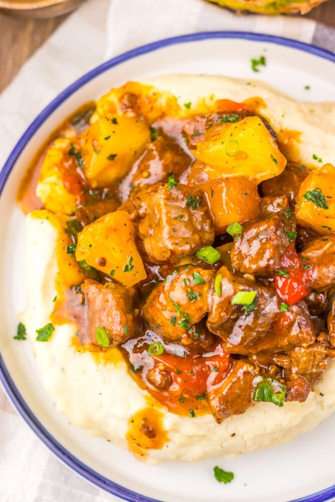 Delicious beef stew with potatoes, carrots, and herbs served over creamy mashed potatoes. Perfect co.