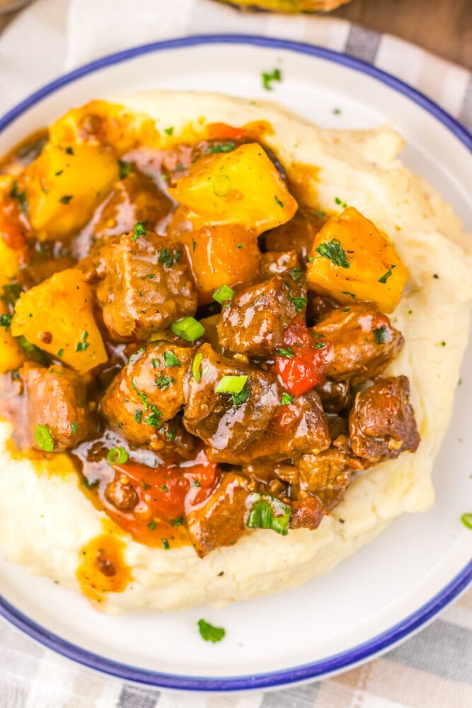 Hearty beef stew with tender meat, potatoes, carrots, and peppers served over creamy mashed potatoes.