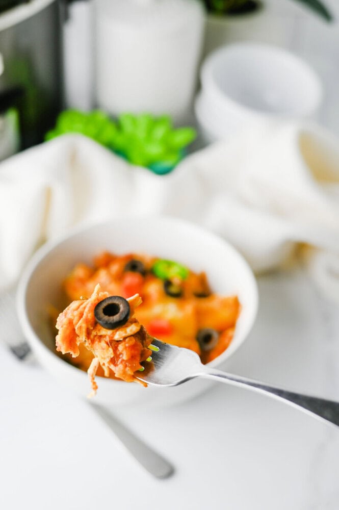 Close-up of creamy spaghetti topped with black olives on a fork.