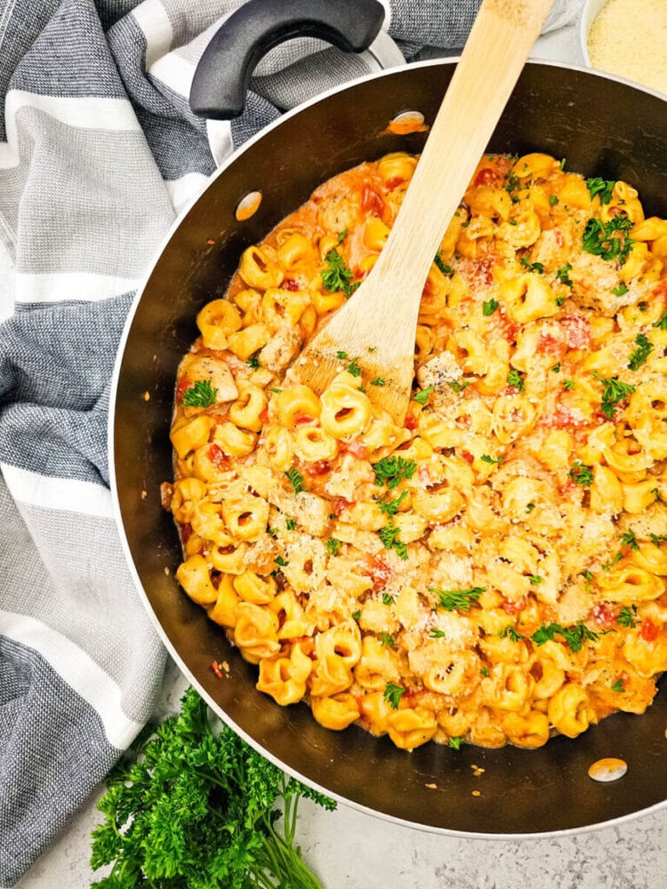 Delicious creamy tomato pasta in a black skillet with herbs.