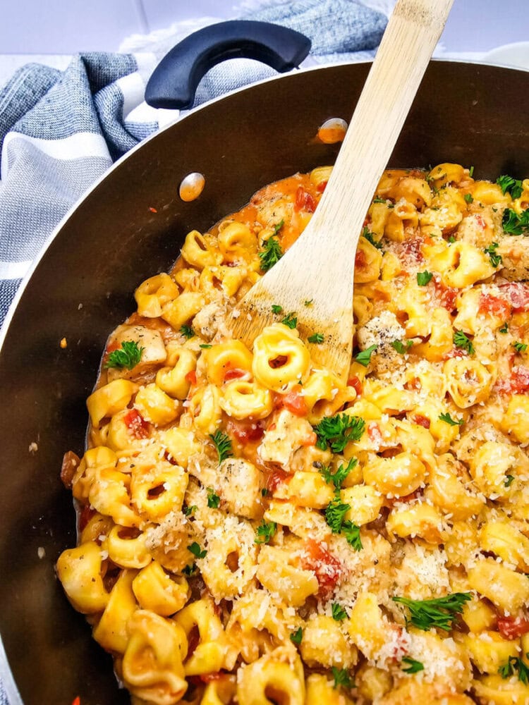 Creamy pasta with tomatoes, herbs, and grated cheese in a skillet.
