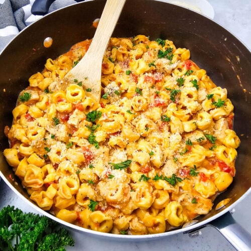 Creamy pasta with tomato, herbs, and cheese in a skillet.