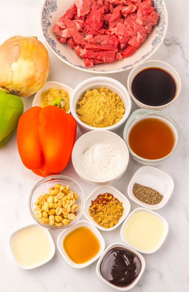Assorted fresh ingredients for beef stir-fry including beef, bell peppers, onion, and sauces.