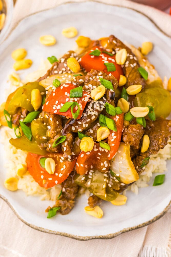 Stir-fried beef with colorful vegetables and corn on a white plate.