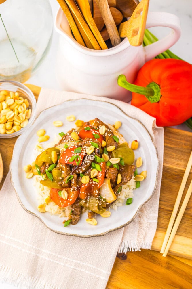 Slow Cooker Kung Pao Beef served on white plate with rice, cashews, and vegetables overhead view
