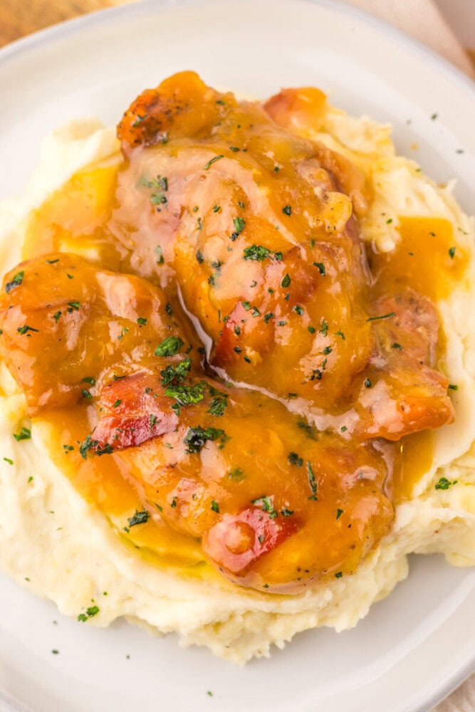Chicken with gravy served over mashed potatoes with herbs.