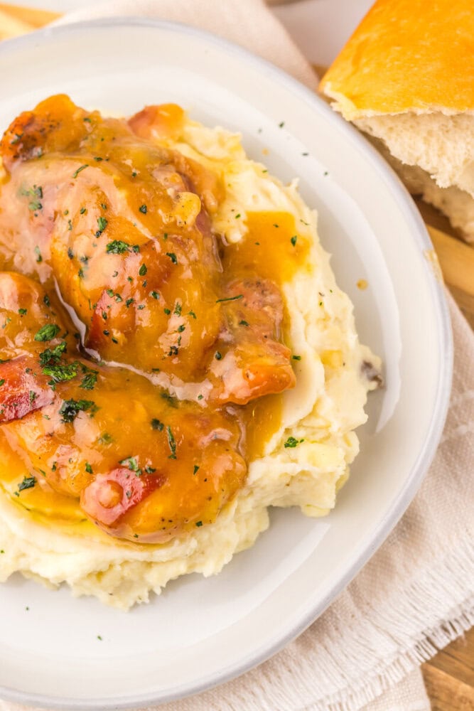 Hearty chicken with gravy served over creamy mashed potatoes with bread on the side.