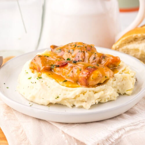Creamy chicken served over mashed potatoes with bread on the side.