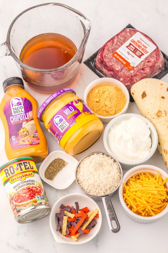 Ingredients for ground beef taco dip including beef, cheese, sour cream, and seasonings.
