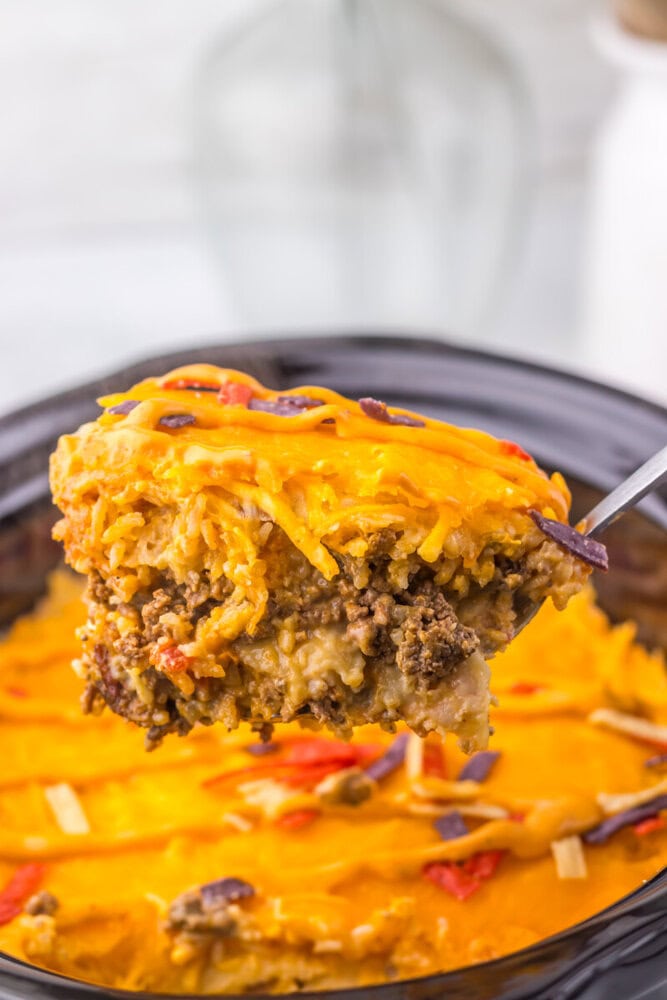 Slow cooker taco bell grilled cheese burrito casserole with melted cheddar cheese and ground beef served in a skillet
