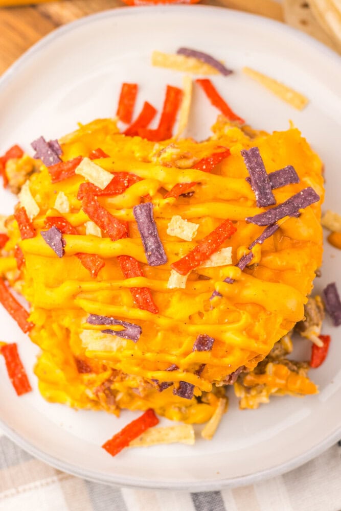Delicious cheesy beef enchiladas topped with colorful shredded cheese and vegetables.