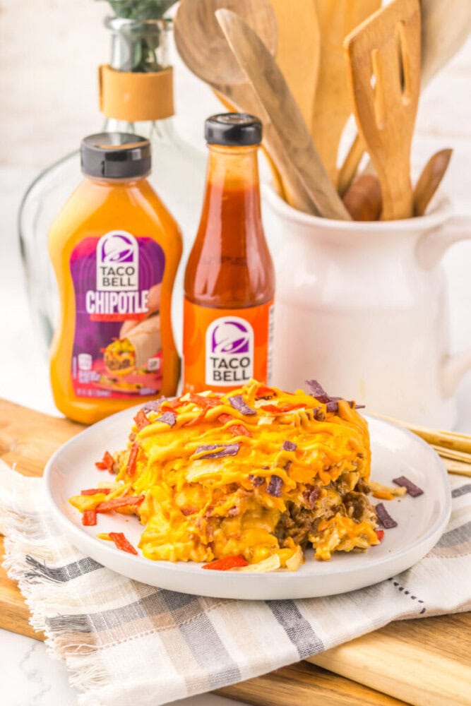 Delicious cheesy taco casserole with beef, cheese, and toppings on a white plate.