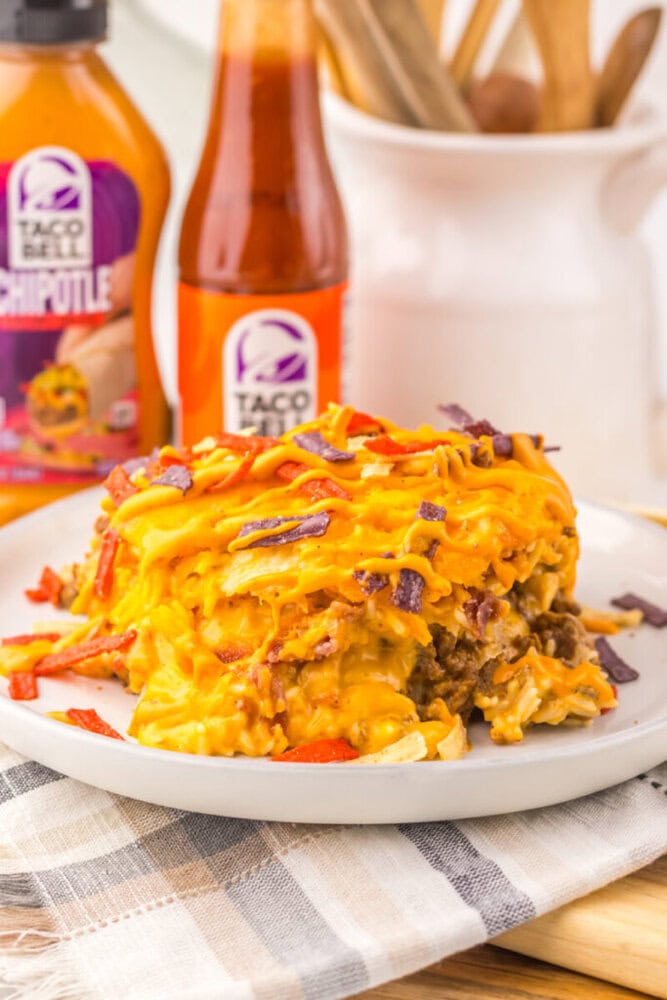 Delicious taco casserole with melted cheese and seasoned beef on a white plate.