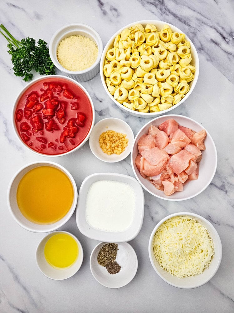 chicken tortellini skillet ingredients laid out in bowls including tortellini, chicken, tomato sauce, cheese, and seasonings