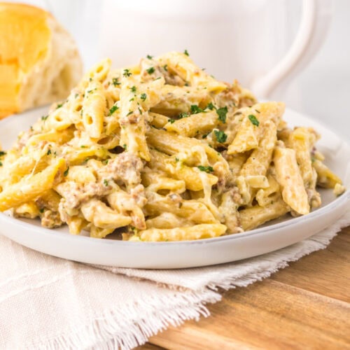 Creamy chicken pasta with herbs served on a white plate.