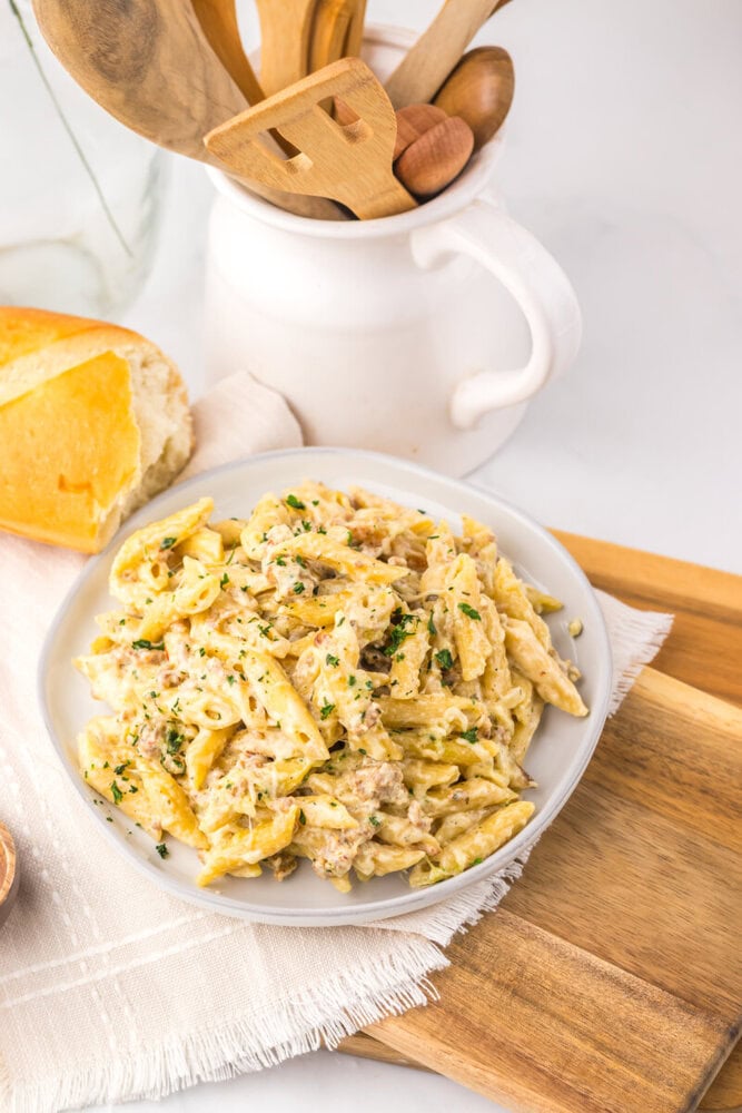 Creamy chicken pasta dish with herbs served on a white plate.