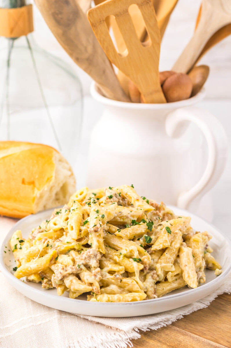 Creamy chicken pasta dish with herbs and sauce on a white plate.