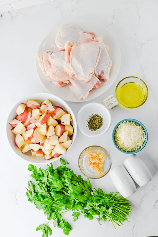 Raw chicken, chopped potatoes, herbs, cheese, and fresh parsley for soup.